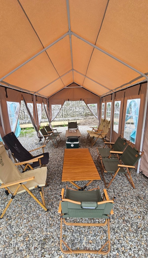 텐트에는 캠핑 느낌이 물씬 나는 테이블과 의자, 야전침대가 놓여있다