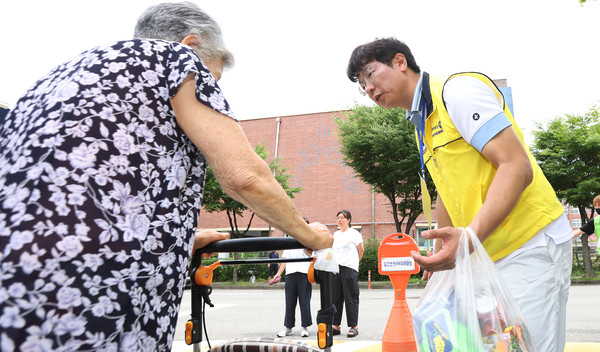 성기경 일산자유로로터리클럽 회장이 어르신에게 꾸러미를 전달하며 안부 인사를 하고 있다.