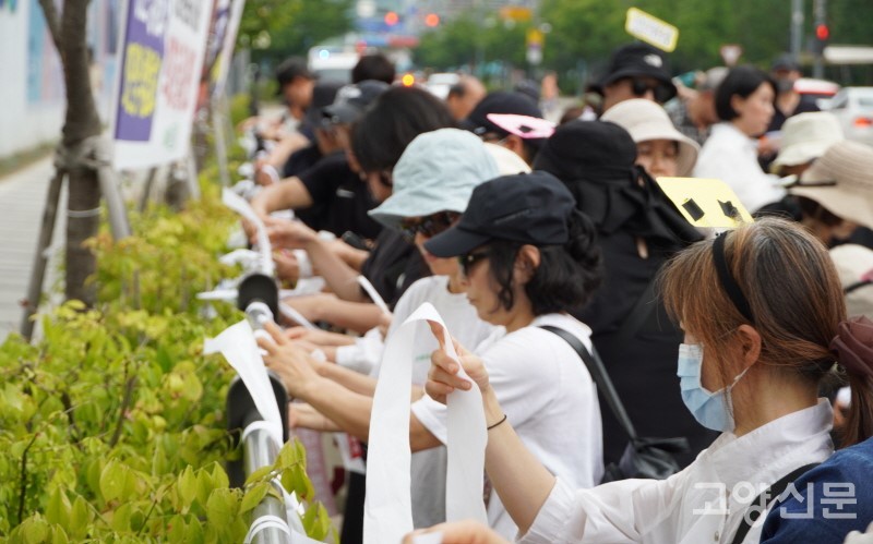 집회를 마친 참가자들이 손에 두르고 있던 구호 리본을 도로 옆 펜스에 묶고 있다.  