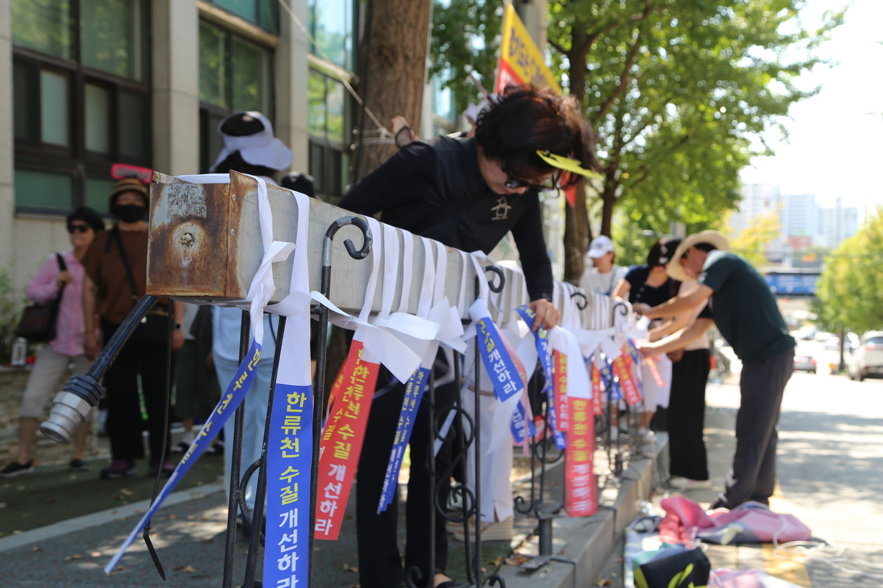 시위 참가자들이 '한류천 수질 개선하라'는 리본을 매달고 있다.