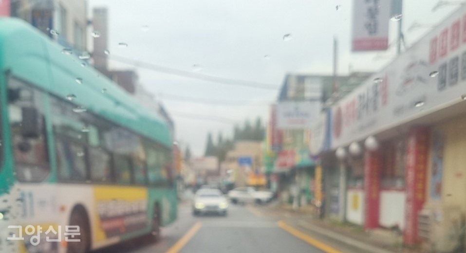 '고양시청.덕양구보건소' 버스정류장에 멈춰있는 버스를 뒤차가 추월하고 있다.