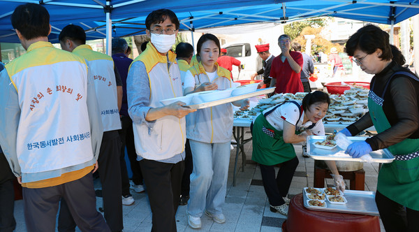 한국동서발전 일산발전본부 직원들과 능곡동새마을부녀회원들이 분주하게 음식을 나르고 있다.