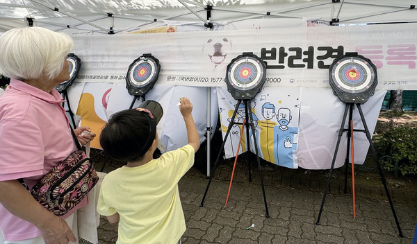 할머니와 함께 나온 어린이가 다트를 하고 있다.