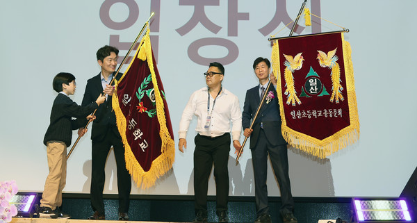 일산초등학교 깃발을 일산초교 교감과 학생, 총동문회장이 흔들고 있다.