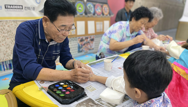 한 어르신이 페이스페인팅 봉사를 하고 있다.