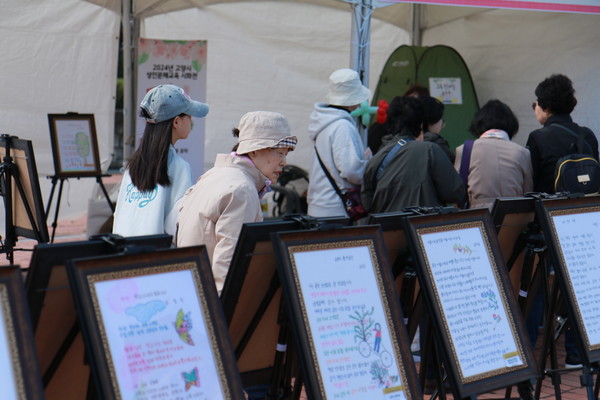 성인문해교육에 참여하고 있는 70, 80대 어르신 학습자들이 쓴 시화를 시민들이 감상하고 있다. [사진제공=고양시 평생학습과]