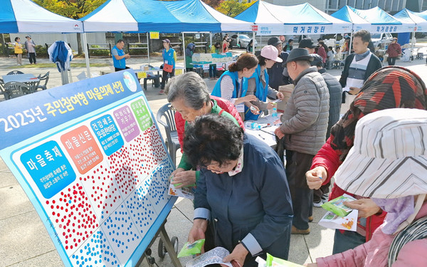성사2동 2024 주민총회 및 어울림축제에서 마을의제에 스티커를 붙이고 있다.