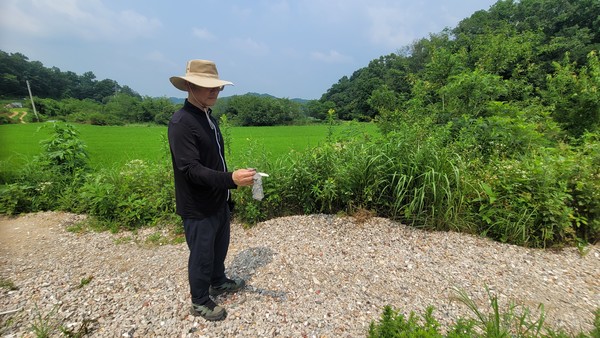 최용석 파주환경운동연합 집행위원장이 진동면 서곡리 농경지 주변에 수북이 쌓인 폐기물을 들고 있다.