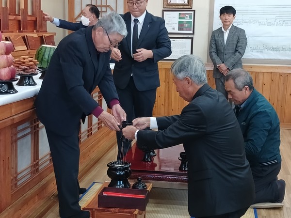    헌관이 집사에게 잔을 전하고 위패 앞에 잔을 올리고 있다.