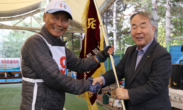 지난해 우승팀인 호수분회가 임은택 이사장(오른쪽)에 우승기를 반납하고 있다.