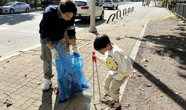 참여 가족이 공원에서 쓰레기 줍는 봉사활동을 하고 있다.