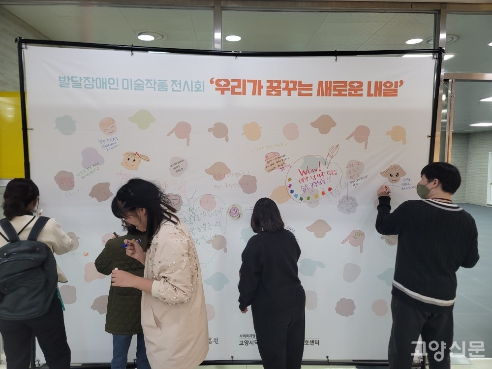 전시회에 참여한 발달장애인들이 방명록을 작성하는 모습