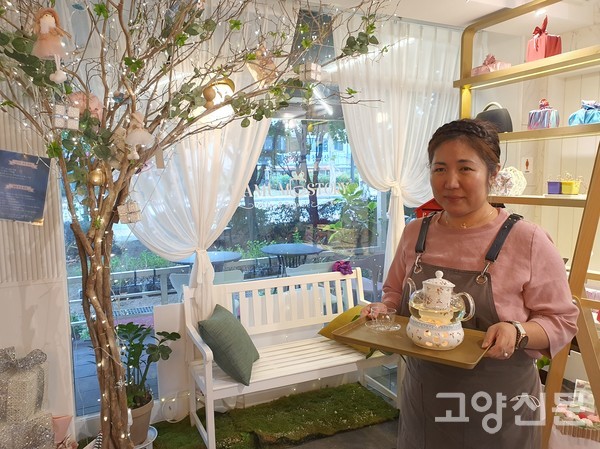 카모마일(허브)차를 고객에게 내기 위해 나무조형물 포토존 앞을 지나고 있는 전정은 대표.