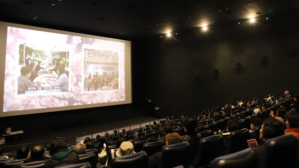 자원봉사자와 후원자, 마을활동가들의 2024년 활동 모습을 담은 영상과 사진을 보고 있는 참석자들.