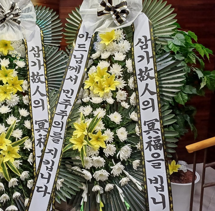 일산복음병원 장례식장에는 ‘삼가 고인의 명복을 빕니다’라는 문구와 함께 ‘아드님께서 민주주의를 지킵니다’라고 적힌 화환이 도착했다. 통상 화환에는 보낸 이의 이름이나 직함·소속이 적혀 있지만, 이 화환에는 이러한 정보가 보이지 않았다. 