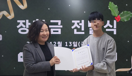  윤영 관장이 한 학생에게 장학금을 전달하고 있다.