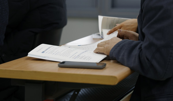 후보 예정자가 설명회에 참석해 설명회를 들으며 자료집을 보고있다.