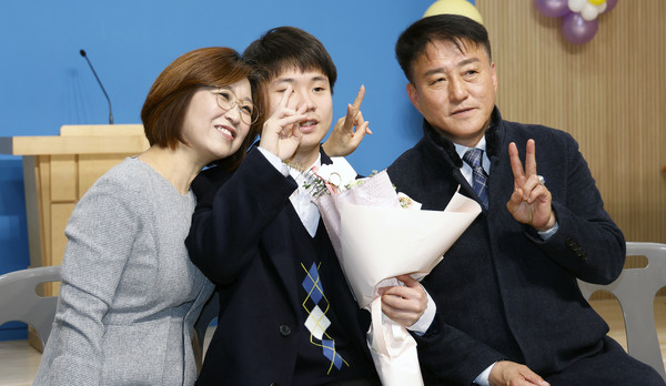 김정민 교감(왼쪽)과 졸업생, 김봉진 교장(오른쪽)이 학생의 졸업을 축하하며 기념사진을 찍었다.