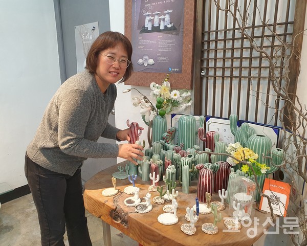 정지은 도예가가 자신의 대표작품인 선인장화병과 반지걸이 앞에서 미소를 짓고 있다.