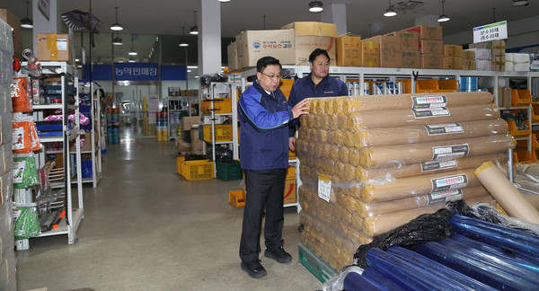 우상훈 조합장이 농업용자재 판매장에서 직원들과 이야기를 나누며 자재를 보고 있다. 