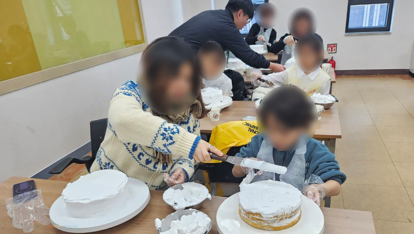 참여자가 부모의 도움을 받아 케이크를 만들고 있다.