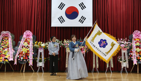 연합회기를 전달받은 김정임 신임회장이 환하게 웃고 있다.