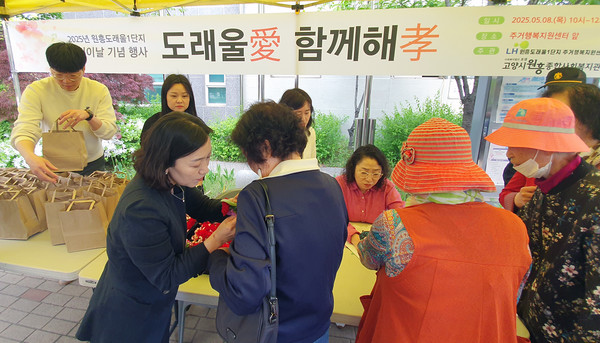 원흥종합사회복지관의 '도래울애 함께해효' 행사. 어르신들에게 카네이션을 달아들이고 있다.