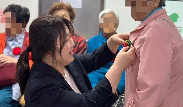 한 직원이 어르신에게 꽃을 달아드리고 있다.