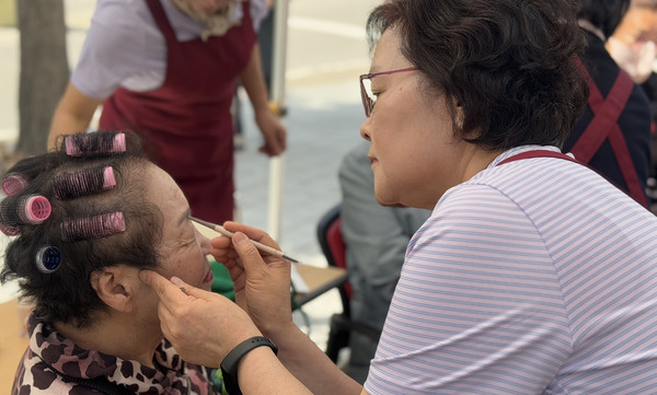 미용봉사자가 어르신에게 화장을 하고 있다.