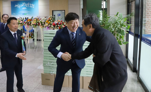 홍성규 신도농협 조합장(가운데)이 조합원을 반갑게 맞이하고 있다.