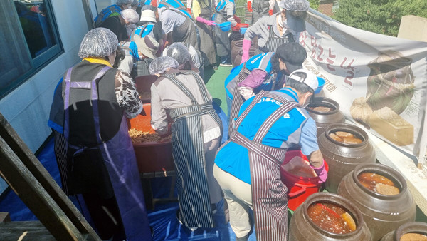 주민자치위 회원들이 장독에 정성스럽게 장을 담그고 있다. 