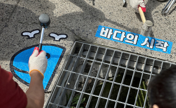  바다의 시작 & 고래 스티커를 배수구 주변에 붙이고 있다.