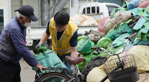 심은보 조합장이 조합원이 싣고 온 재활용 폐농자재를 나르고 있다. 