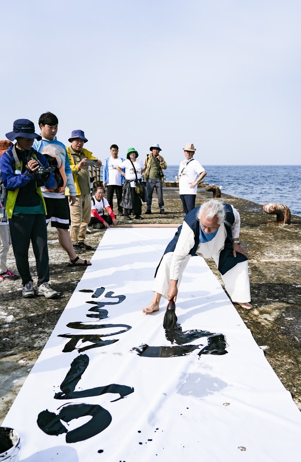 동도 선착장 앞에서 송동옥 화백이 큰붓으로 ‘우산도가 독도다’라는 글씨를 쓰고 있다. 