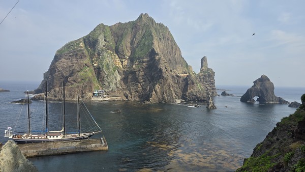 괭이갈매기들이 범선 코리아나호를 따라 독도를 돌고 있다. ​​‘2025 범선 타고 독도 가자’ 탐사대원들이 동도 부두에 도착한 뒤 서도를 배경으로 기념 사진을 찍고 있다. 
