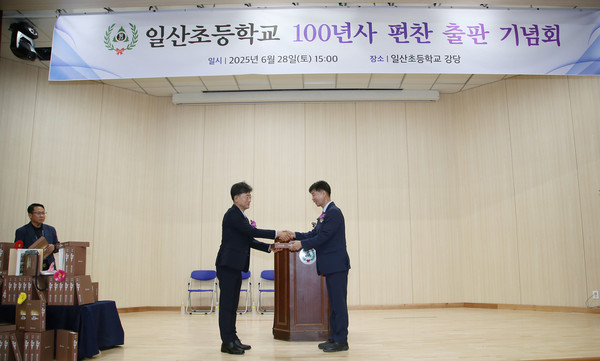 김광수 일산초교 교장(왼쪽)에게 100년사를 전달하는 박광석 편찬추진위원장.