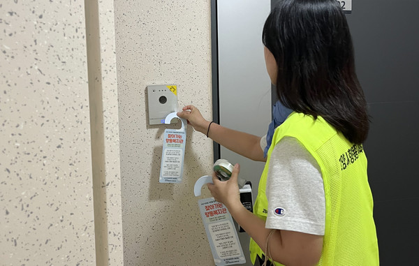 향동종합사회복지관 직원이 문고리 홍코 캠페인을 하고 있다.