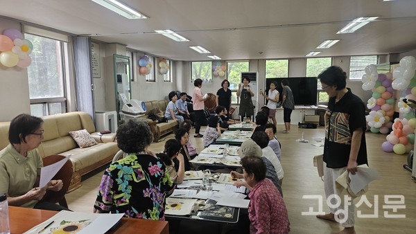  재능나눔 강사가 어르신들에게 에코백에 그림 그리기를 가르쳐드리고 있다.