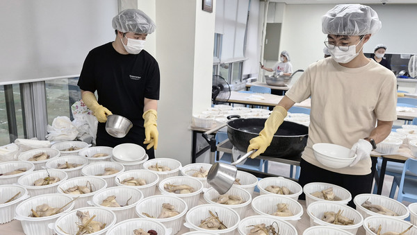  삼계탕을 전달하기 위해 정성스럽게 그릇에 담는 봉사자들.