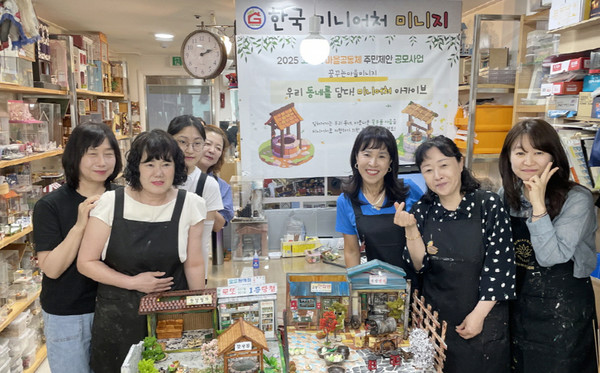  ‘꿈꾸는마을 미니지’ 공동체가 꽃우물이 있는 마을 미니어처 앞에 함께 자리했다.