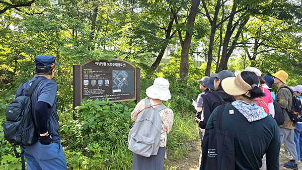  마을숲 탐사단이 영주산 들머리에서 야생생물보호구역 표지판을 둘러보고 있다.