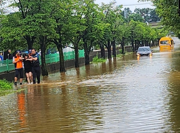 화정동 명지병원 건너편 거창농원 앞 도로. 한 여성 운전자가 침수된 차량에서 겨우 빠져나와 119에 구조요청을 했으나 지역 곳곳이 침수돼 경찰관과 의용소방대가 40여분 만에야 도착했다. 경찰관과 의용소방대가 여성 운전자를 부축해 병원으로 이송하고 있다. [제보·사진=이해경 독자]