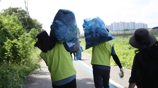 봉투 가득 담긴 쓰레기를 어깨에 메고 한군데에 모으기 위해 옮기는 회원들.