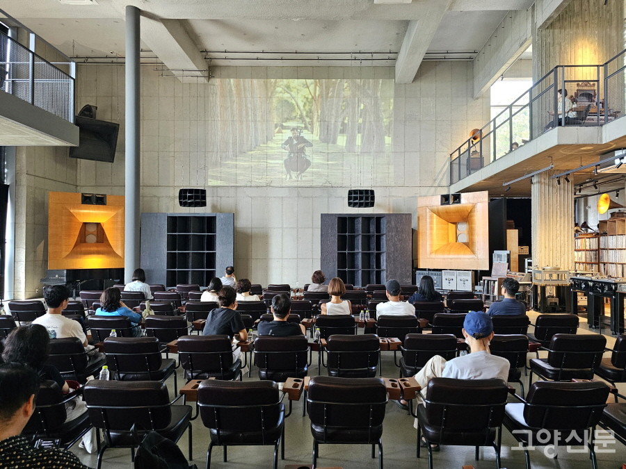 벽면에 상영되는 연주 영상을 감상하며 음악을 즐기고 있는 관람객들. 