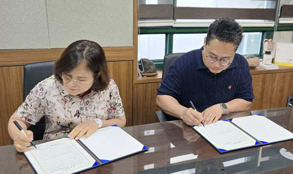 두 기관장이 협약서에 서명을 하고 있다.