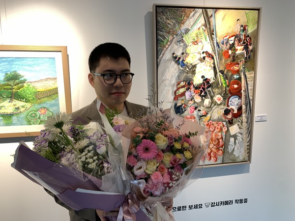 수상작 '김장(오른쪽 그림)'을 배경으로 기념사진을 찍고 있는 유영철 작가.