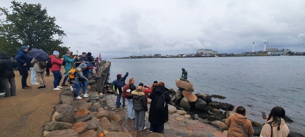 흐린 날씨에도 덴마크 코펜하겐 인어동상 앞에 관광객들이 모여있다.