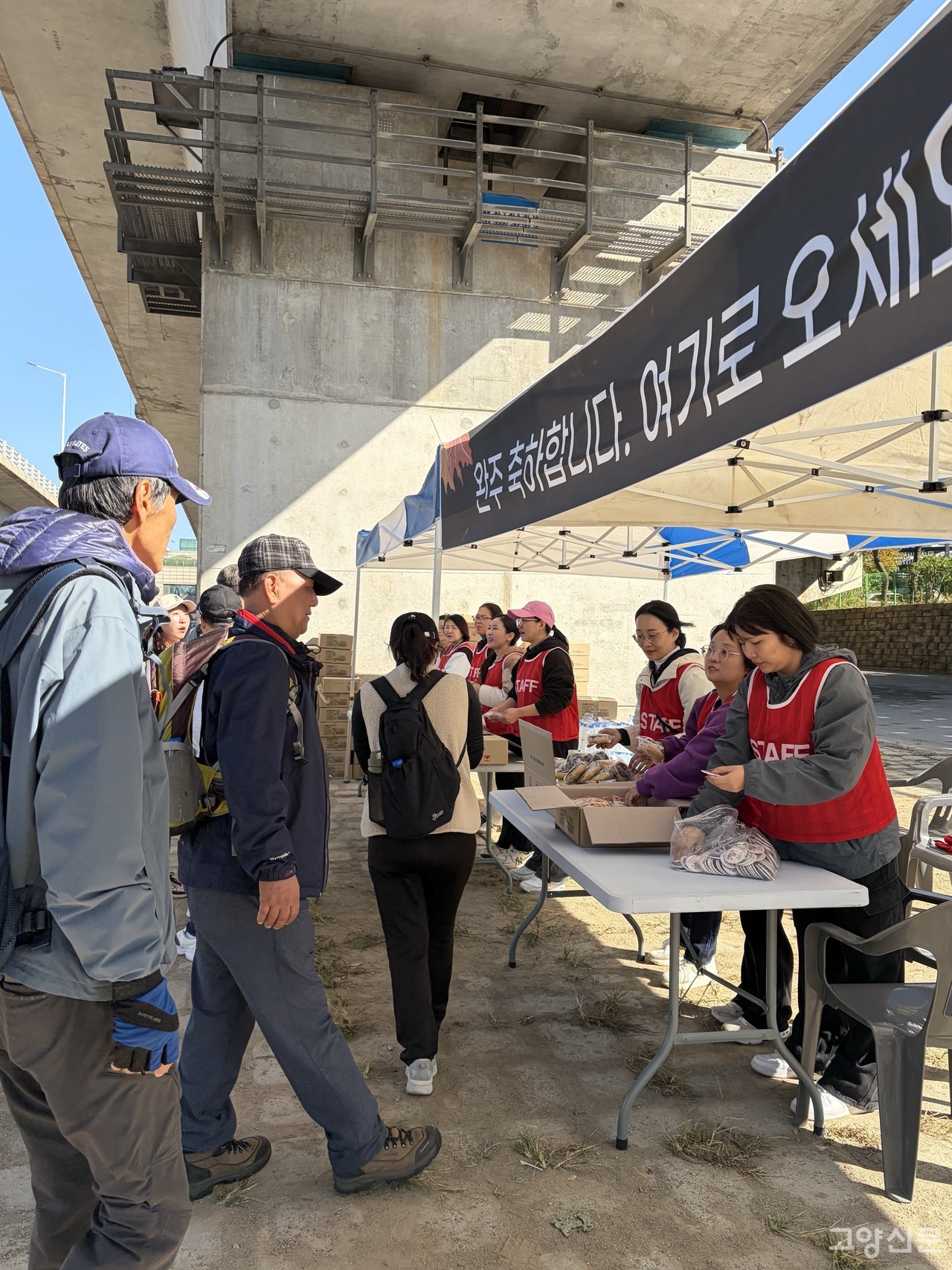 "완주를 축하합니다!" 완주자들이 기념배지와 간식을 받고 있다.