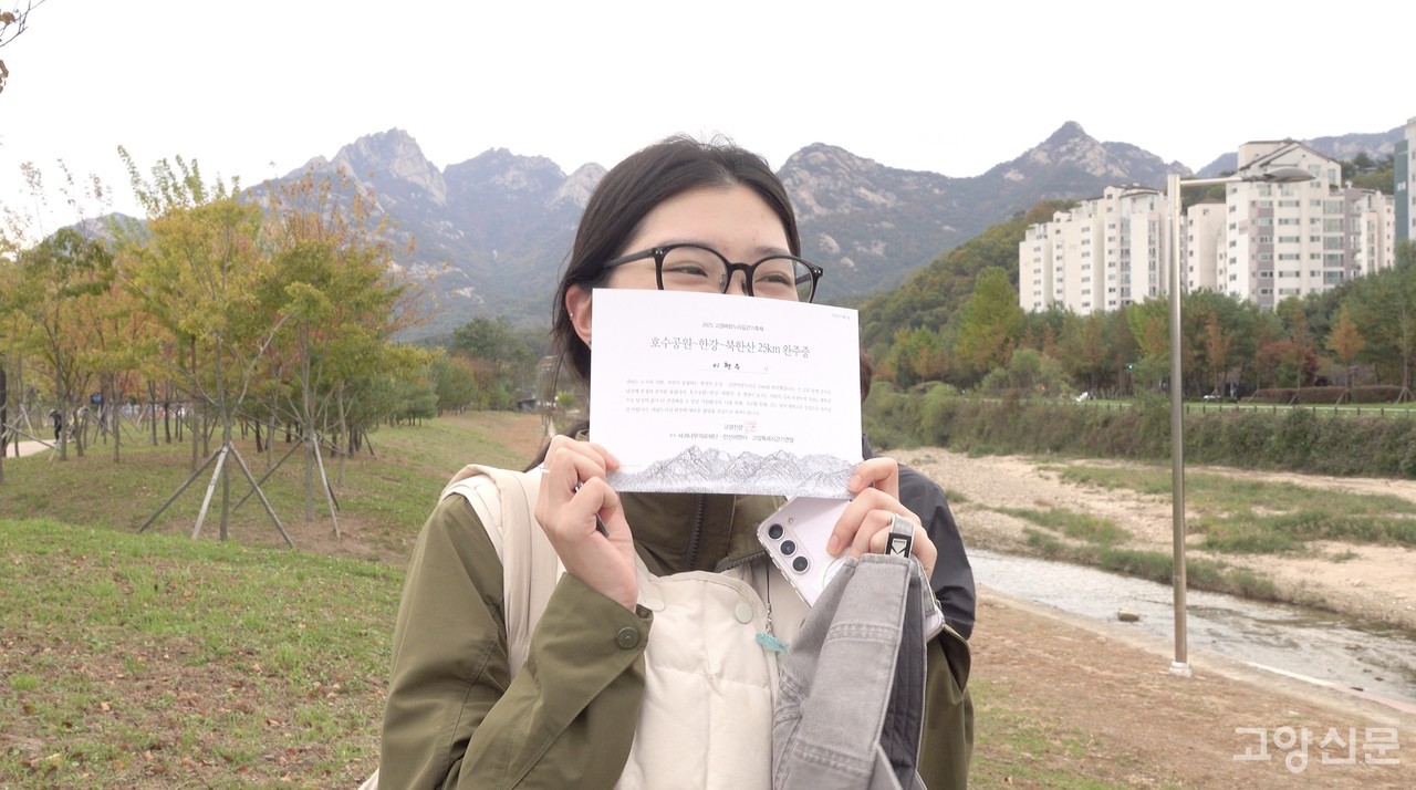 완주증을 받아든 참가자가 북한산을 배경으로 환하게 웃고 있다.