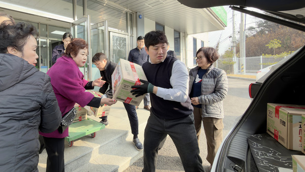 고양축산농협 부녀회원들이 김장을 전달하기 위해 직원들과 차에 김치를 싣고 있다.